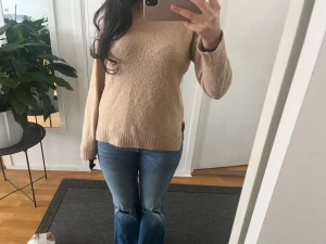 Stickad tröja  - Mysig beige stickad tröja med rund halsringning och långa ärmar. Tröjan har en rak passform och ribbstickade muddar vid ärmslut och nederkant. Perfekt att matcha med jeans för en avslappnad look. NOPPRIG!