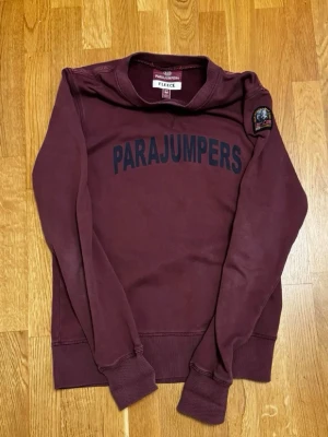Parajumpers Tröja - Säljer en vinröd sweatshirt från Parajumpers med tryckt logotyp framtill och patch på ärmen. Storlek M. QR-kod till Certilogo finns som äkthetsbevis. Gott skick, se bilder.