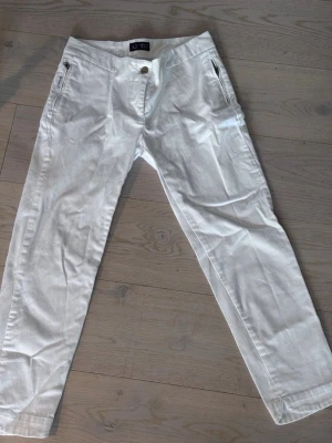 Vita jeans  från AJ Jeans - Snygga vita linnebyxor från AJ Jeans med raka ben och dragkedjefickor fram. Byxorna har en klassisk passform och är tillverkade i ett luftigt linnematerial, perfekta för varma dagar. Stängs med knapp och dragkedja framtill.