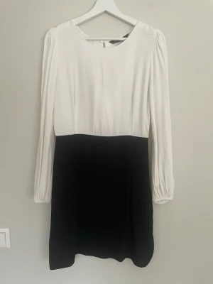 Svartvit klänning från Zara Woman - Snygg svartvit klänning från Zara Woman med långärmad design och rund halsringning. Klänningen har en klassisk tvåfärgad look med vit överdel och svart kjoldel. Tillverkad i ett mjukt och lätt material som ger en stilren och modern känsla.