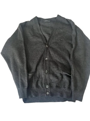 Wolsey kofta - Klassisk mörkgrå kofta med v-ringning från wolsey. Koftan har knäppning framtill med sex knappar, två fickor och diskret broderad logga på bröstet. Tillverkad i mjukt material, perfekt för lager-på-lager och kalla dagar.