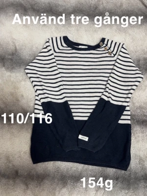 Randig marinblå och vit tröja - Snygg randig tröja från Newbie i marinblått och vitt. Tröjan har knappar på axeln . Perfekt för en stilren look med långa ärmar och klassiskt mönster.🌸Använd tre gånger. Storlek 110/116