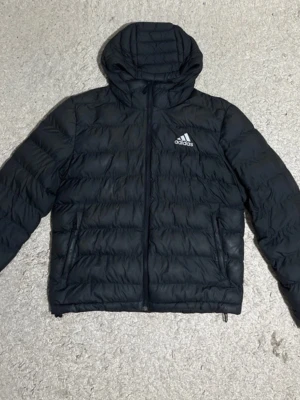 Adidas pufferjacka svart storlek M - Säljer en snygg adidas pufferjacka som har storleken M. Perfekt för dom kalla dagarna i vintern då den värmer bra.                                Skickas snabbt, hör av dig vid frågor eller om du vill ha fler bilder! 
