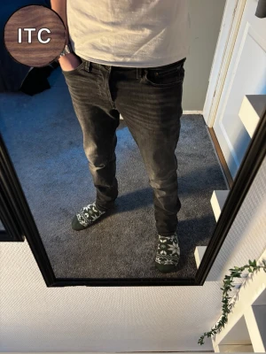 Jack & Jones jeans  - Säljer ett par svarta jeans från Jack & Jones med snygg tvättad look och klassisk femficksdesign. Jeansen har en tapered passform som sitter skönt över låren och smalnar av mot anklarna. Perfekta för dig som gillar en modern och avslappnad stil.