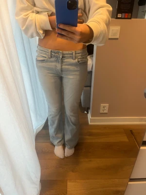 Bootcut ljusblå jeans  - Snygga ljusblå bootcut jeans med klassisk femficksdesign och bälteshällor. Jeansen har raka ben med lätt utsvängning och är tillverkade i mjukt denimtyg. Perfekta för dig som gillar retrovibbar och vill ha en chill look.