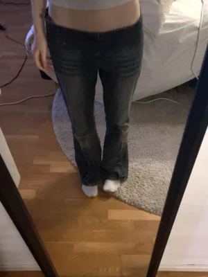 Mörkblå bootcut jeans med detaljer - Säljer ett par mörkblå jeans med låg midja och bootcut passform. Midja 76 och innerbenslängden 80