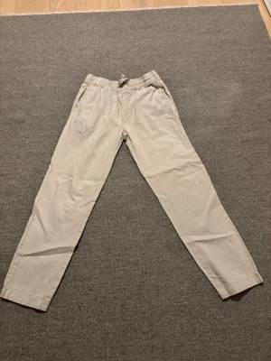 Beige linnebyxor - Snygga beige linnebyxor från Cubus  i storlek S. Byxorna har en avslappnad passform med elastisk midja och snörning framtill. Tillverkade linne perfekta för varma sommar dagar