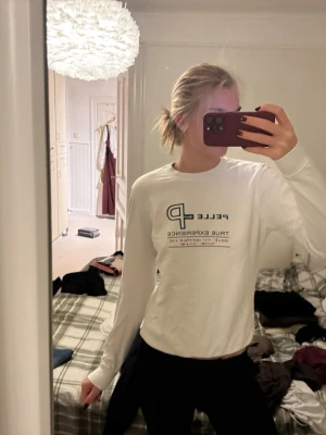 Vit långärmad tröja från Pelle P - Säljer en vit långärmad tröja från Pelle Petterson med tryck på bröstet. Tröjan är i bomull och har en klassisk passform med rund hals. Perfekt till chill dagar eller när du vill ha en clean look.