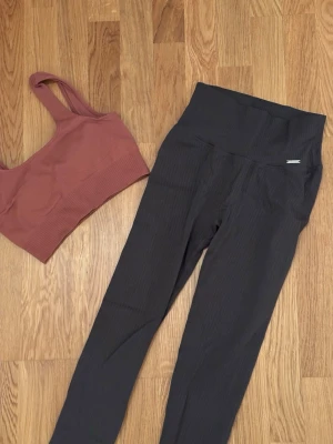 Träningssett Aimin - Nyskick! Ribbade träningstights och sporttopp med vaddering i från Aimin. Tightsen är mörkgråa och toppen är gammelrosa. Storlek S i båda. 
