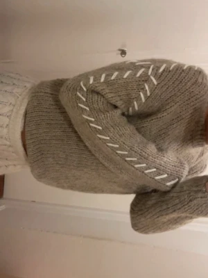 Beige stickad tröja med vit snörning - Säljer en beige stickad tröja med lång ärm och cool vit snörningsdetalj längs armarna. Tröjan har en loose passform och är perfekt för dig som gillar mysiga och trendiga plagg. Passar extra bra under höst och vinter.