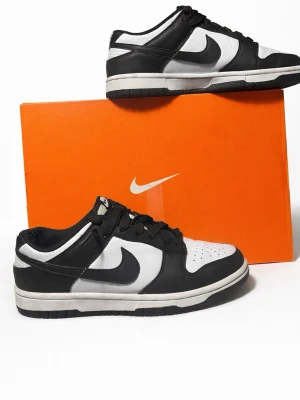 Nike Dunk Low svart/vit sneakers - Nike Dunk Low sneakers i svart och vitt med klassisk Swoosh-logga på sidan. Skorna har snörning, rund tå och platt sula. Ovandelen är tillverkad i skinn och syntet, med perforeringar på tån för extra ventilation. Perfekt för dig som gillar stilrena och ikoniska sneakers.