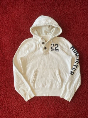 Hollister huvtröja - Hollister hoodie i storlek L. Liten fläck på framsidan samt lite nopprig. Jag på bilden är 180 cm. Mått: axelbredd - 45 cm, armhåla till armhåla - 55 cm, längd - 62 cm. Skriv för fler bilder och frågor!