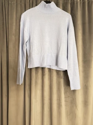 Ljusblå stickad polotröja H&M Divided - Aldrig använd, Säljer en ljusblå stickad polotröja från H&M Divided i storlek S. Tröjan har ribbad polokrage, ribbade muddar och nederkant samt lång ärm. Croppad passform som ger en trendig look. Perfekt att styla med jeans eller kjol.