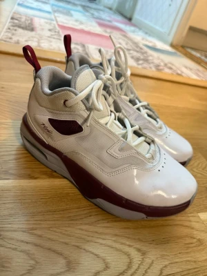 Nike Jordan stay loyal 3 - Nike Air sneakers i vit och vinröd färg med högt skaft och snörning. Skorna har mesh och skinnmaterial, rund tå och platt sula. Snygga detaljer med vinröda inslag på sidan och bak, samt tydlig Nike Air-logga på sulan. Har andvänts ca 3 gånger. Storlek 36 1/2.