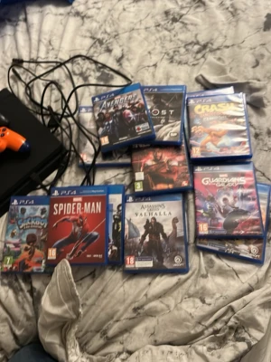 PlayStation 4 med två kontroller och spel - PlayStation 4 i gott skick med två DualShock 4-kontroller (svart och orange).Flera populära spel ingår, bl.a. Spider-Man, Crash Bandicoot, Assassin's Creed Valhalla och Guardians of the Galaxy. Alla kablar medföljer. Perfekt för spelentusiasten! Pris kan diskuteras vid snabb affär.