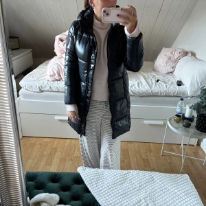 Marinblå dunjacka från save the duck - Marinblå lång dunjacka från save the duck med glansig material. Jackan har luva, två sidofickor. Tål regn. Köpt för 4500 kr användes förra vintern. Är helt som ny inga defekte förutom (bild) på dragkedjan.