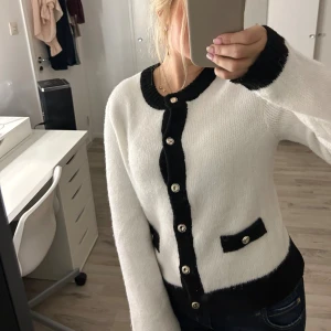 Vit och svart kofta från New Yorker - Superfin vit kofta från Amisu med svarta detaljer längs kanterna, knappar framtill och dekorativa fickor. Mjuk och stickad känsla, perfekt för lager-på-lager. Rund halsringning och långärmad modell som ger en klassisk look.