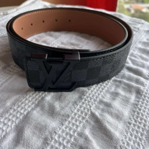 L-bälte  - Snyggt L-bälte i Damier-mönster med svart spänne. Aldrig använt, Storlek: 110 cm