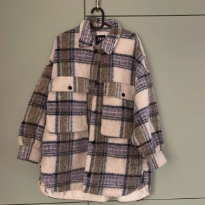 Rutig kappa från Zara - Säljer en oversized kappa från Zara i mjuk ullmix. Jackan har stora fickor på bröstet med knappar, klassisk krage och långa ärmar. Perfekt för lager-på-lager inför hösten❣️