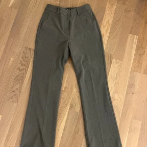 Grå kostymbyxor med bootcut - Grå kostymbyxor med bootcut och pressveck. Mjukt och bekvämt material. Medel/låg midja.