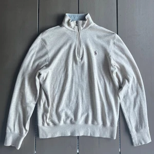 Beige half zip tröja från Polo Ralph Lauren - Snygg beige långärmad tröja från Polo Ralph Lauren med klassisk broderad logga på bröstet. Tröjan har en hög krage med half zip-dragkedja och är tillverkad i mjuk bomull. Perfekt för lager-på-lager och chill vibes.