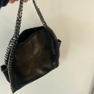 Svart väska med kedjedetaljer - Säljer liknande Stella McCartney väska, säljer pågrund av att det ej kommer till användning. Använd ca 3 gånger. Hör gärna av för fler bilder💕