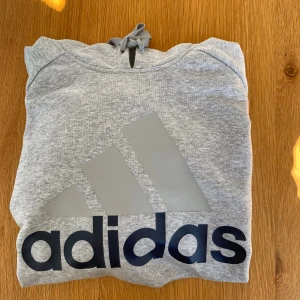 Grå hoodie - Grå hoodie från Adidas.   Rensar ur min garderob från en hel del oanvända kläder🌼 Om du ser något mer i min profil som du gillar så skickar jag med det till dig också!😊 Fler kläder kommer! 