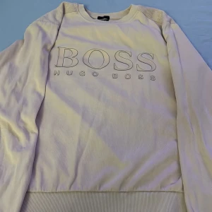 Vit Hugo Boss sweatshirt slim fit - Vit sweatshirt från Hugo Boss med stort BOSS-tryck framtill. Tröjan har rund halsringning, långa ärmar och ribbade muddar. Tillverkad i mjuk bomullsmix för en clean och stilren look. Perfekt för dig som gillar klassiska märken och enkel design. Helt acceptabelt skick 7,5/10🔥
