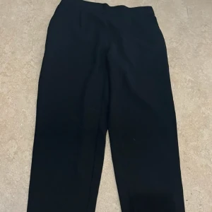 Svarta kostymbyxor i rak modell - Svarta kostymbyxor från Cubus i rak och klassisk modell. Byxorna har resår i midjan för extra komfort och är perfekta för en stilren look. Passar dig som gillar enkel och clean stil.