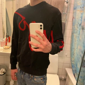 Svart sweatshirt Hugo Boss - Riktigt snygg unik sweatshirt från Hugo Boss med den broderade röda texten Hugo över bröstet och ena ärmen. Tröjan är i bra skick, storleken är M