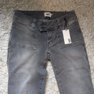 Grå bootcut jeans - Snygga grå jeans från 157 med bootcut passform och stora framfickor. Jeansen har en cool tvättad look, bred linning med dubbla knappar och är tillverkade i mjukt denimtyg. Perfekta för dig som gillar en avslappnad men trendig stil. Aldrig använda bara att lappen åkte av när jag testade. Passar folk som är runt 165 och i storlek S☺️ Köp dem helst på vinted om ni vill för hör tar de en viss summa☺️