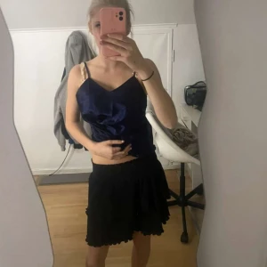 Svart volangkjol i kort modell - Säljer en svart kort kjol med volangkant från kaphal