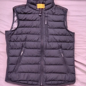 Svart dunväst från Parajumpers y-s  - Snygg svart Parajumpers-dunväst (Y-S, junior som motsvarar ungefär 10 -12 år). Västen är äkta och i mycket fint skick! Samtligt att ny pris är runt 4500kr. Använd endast 2 gånger och är 10/10 i skick.