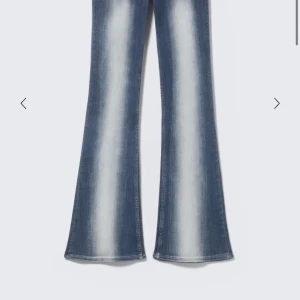 Blå bootcut jeans med ljusa detaljer - Säljer ett par blå bootcut jeans med snygga ljusa tvättade partier längs benen. Jeansen har låg midja och klassisk femficksdesign. Materialet är jeans och passformen är normal med utsvängda ben för en retro vibe. Storlek är w28 L30