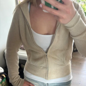 Beige hoodie i kashmir från Soft Goat - Supermjuk beige hoodie från Soft Goat i 100% kashmir. Köpt här på Plick och i fint skick bortsett från att den har fått ett hål på armbågen pga det tunna kashmirtyget, går ju att försöka laga❣️Syns på bilderna men se även sista bilden💗Den är lite nopprig och har en fläck på mudden på framsidan, men det syns knappt. Storlek XS men passar även S. Jag är ca 160🫶