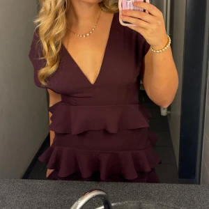 Balklänning  - Supersnygg vinröd klänning från bubbleroom med flera volanger, djup v-ringning och korta ärmar. Klänningen har dragkedja i ryggen och är figurnära upptill. Perfekt för dig som vill sticka ut med en elegant och trendig look. Nypris 1200 använd en gång.