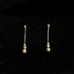 Örhängen äkta silver - Säljer ett par stilrena hängande örhängen i äkta silver med tre små kulor i olika storlekar längst ner på en tunn kedja. Perfekta för dig som gillar minimalistisk och modern design. Stift med transparenta pluppar för extra komfort.