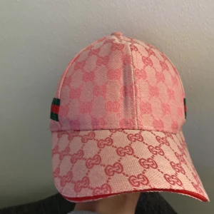 Rosa keps med gröna och röda ränder - Snygg rosa keps med ränder på sidorna och det står GG överallt på den
