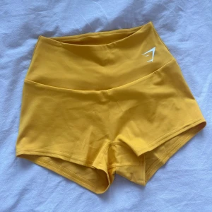 Träningsshorts - Säljer ett par gula träningsshorts från Gymshark i storlek S. Har aldrig använt dessa då jag glömde skicka tillbaka dem! Otroligt mjukt material