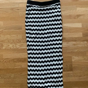 Svartvit långkjol från New yorker - Säljer en stickad långkjol från Amisu i storlek 36. Kjolen har ett vågigt randigt mönster i svart och vitt, elastisk midja och mjukt stickat material. Perfekt för dig som gillar coola mönster och vill ha något som sticker ut.