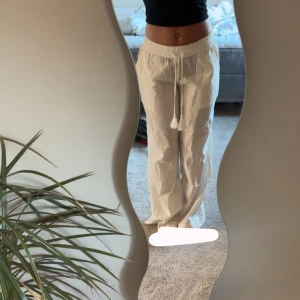 Vita linnebyxor med snörning prislapp, från Nelly  - Säljer ett par vita linnebyxor med avslappnad passform och dragsko i midjan. Byxorna har raka ben och är perfekta för varma dagar. Lätta och luftiga, passar till både strand och city.