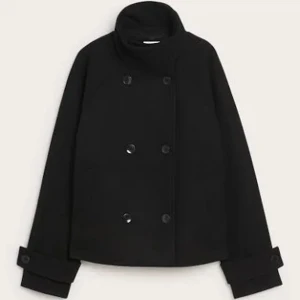 Svart kappa - Stilren svart kappa med dubbelknäppning och hög krage. Jackan har breda manschetter med knappar och en rak, något boxig passform. Perfekt för dig som gillar klassisk och tidlös stil.