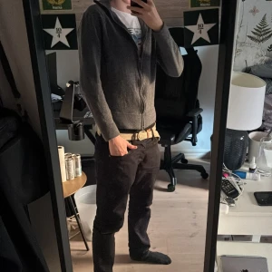 Mörkgrå hoodie från These Glory Days - Snygg mörkgrå hoodie från These Glory Days i mjuk merinoull. Tröjan har dragkedja framtill, hög krage och långa ärmar. Perfekt för dig som gillar stilrena och bekväma plagg med lite sportig vibe. Superior Merino-materialet gör den extra skön. Tröjan är från början storlek L men råkat tvätta den i för hög värme så den sitter som en XS nu