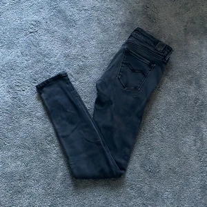 Replay Jeans - Säljer ett par svarta Replay jeans med slim fit och klassisk femficksdesign. Jeansen har en snygg mörk tvätt och diskret Replay-logga på bakfickan. Perfekt passform och stretchigt jeanstyg som sitter bra vid benen