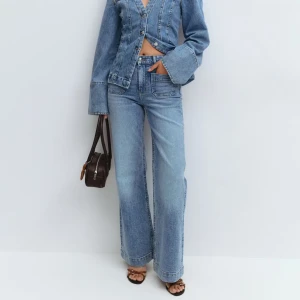 Ljusblå wide jeans med hög midja - (Oanvända ligger kvar i förpackningen med prislapp? Snygga ljusblå jeans med breda ben och hög midja. Klassisk femficksmodell i mjukt denimtyg, perfekt för dig som gillar en avslappnad och trendig look. Passar till både sneakers och klackar för en cool vibe.