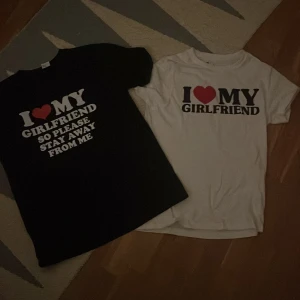 2st T shirts med tryck - Två t-shirts i storlek S med trycket 'I ❤️ MY GIRLFRIEND', en i svart med vit text och en i vit med svart text. Den svarta har även texten 'SO PLEASE STAY AWAY FROM ME'. Båda är i 100% polyester och har klassisk passform med korta ärmar och rund hals. (200kr styck men 350kr om man köper båda)