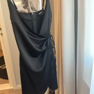 Svart omlottklänning från Bik Bok  - Supersnygg svart kort omlottklänning från Bik Bok. Klänningen är aldrig använd utan endast testad men tyvärr var den förliten för mig!🩷