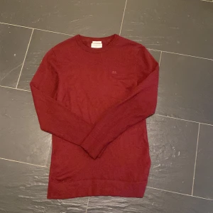 Vinröd merinoullströja från Lindbergh - Snygg vinröd långärmad tröja från Lindbergh i mjuk merinoull. Slim fit-modell med rund halsringning och diskret broderad logga på bröstet. Perfekt för dig som gillar stilrena och bekväma plagg med en clean look. !!! Kom jättegärna med bud då priset inte är fastspikat !!!