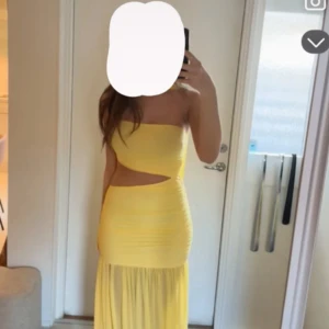 Gul långklänning med cut-out - Snygg gul långklänning med asymmetrisk one shoulder och cool cut-out vid midjan. Klänningen har en figurnära passform upptill och ett flowigt fall nertill. Perfekt för dig som vill sticka ut med en färgstark look.