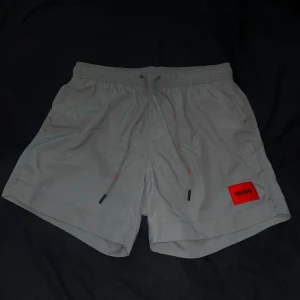 Hugo Boss badbyxor - Hugo Boss grå badbyxor i storlek M. Använda en enda gång.  Modell: Dominica